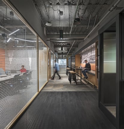 DIRTT's center mount modular glass wall features a custom graphic and divides a hallway workspace and a meeting room.