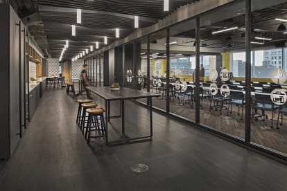 A modular glass wall system separates a classroom from a modern kitchen area that features custom casework.