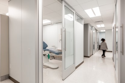 From the hallway we see a private dental treatment area made from DIRTT's glass and solid walls with sliding glass door.