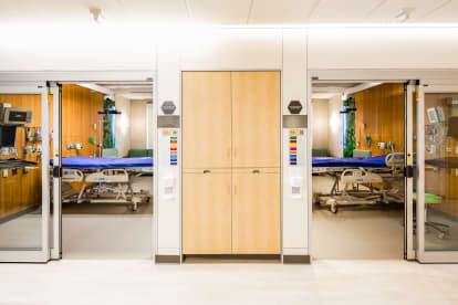 Casework cupboards with open glass sliding doors on each side to patient rooms where DIRTT's headwall solution is visible.