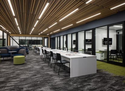 University campus student center built with prefab double pane glass walls, integrated technology, and timber overhead