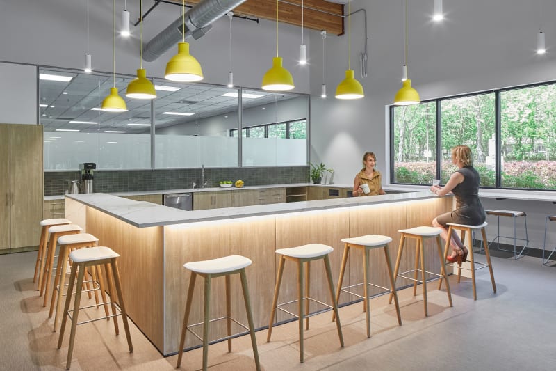 This breakroom area has DIRTT custom casework cabinetry along the back and a large eating bar that wraps around.