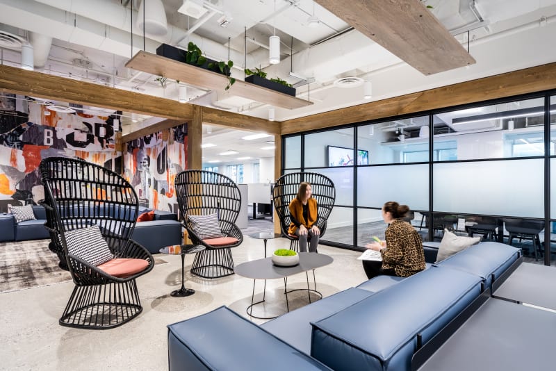 DIRTT's Timber Frame and center mount modular glass wall system flank a casual office meeting space.