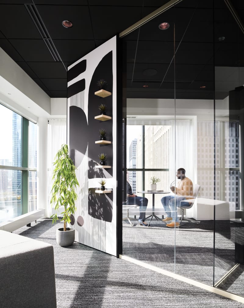 This meeting room features DIRTT's Reflect glass wall system with one solid wall that has custom graphics and shelves.