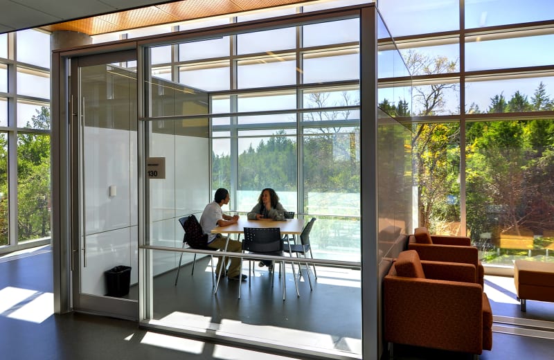 Collegiate academy meeting room built with prefab glass walls and hinged doors