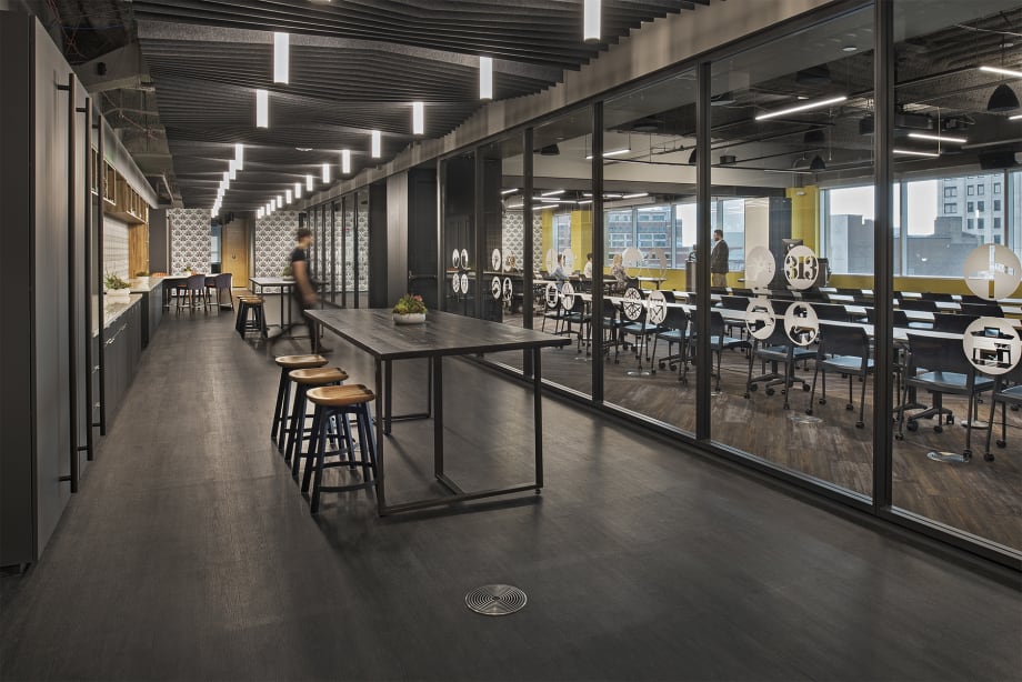 A modular glass wall system separates a classroom from a modern kitchen area that features custom casework.