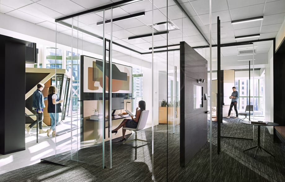 These office spaces are surrounded by DIRTT's Reflect glass wall system with top-mounted sliding glass barn doors.