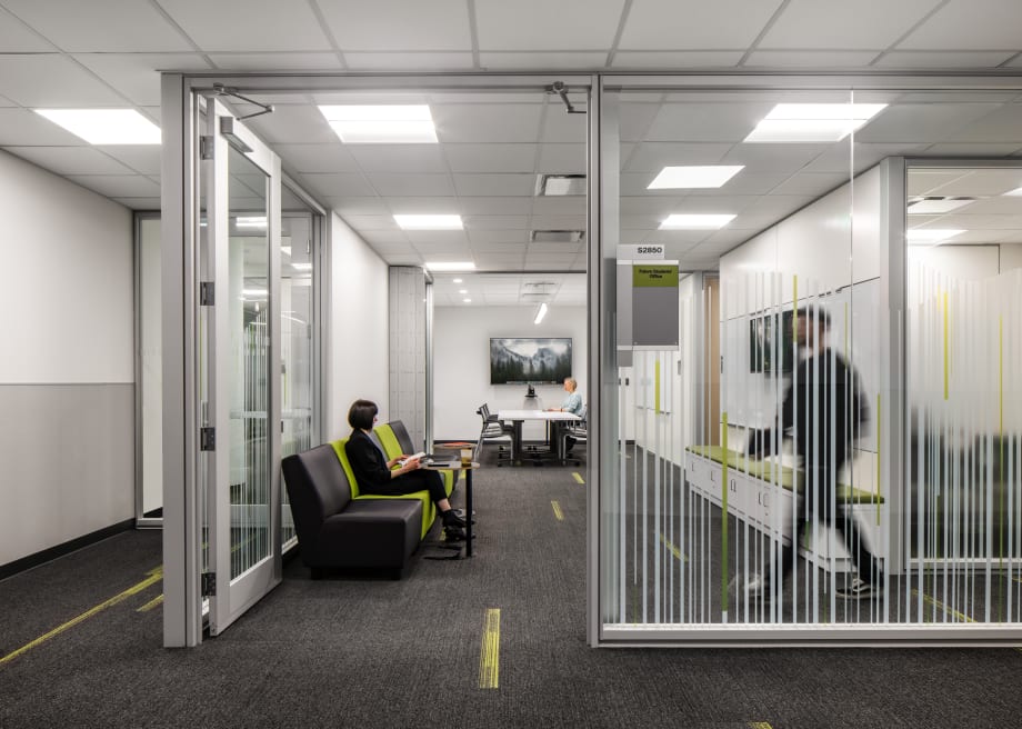 Higher ed office with mounted technology, prefab swing glass doors, and wall graphics