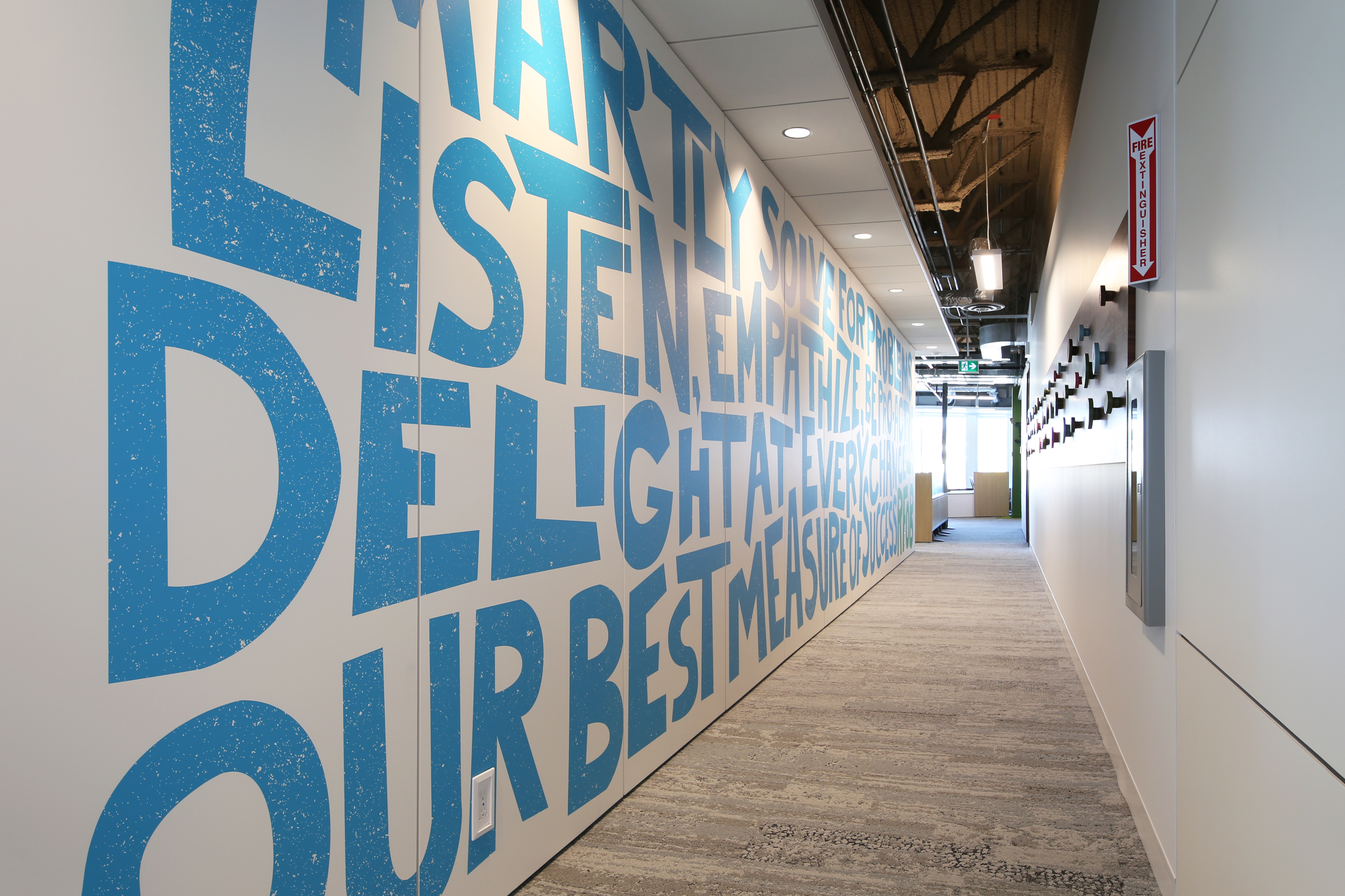 This hallway is lined with a sold modular DIRTT wall that features colorful custom graphics.