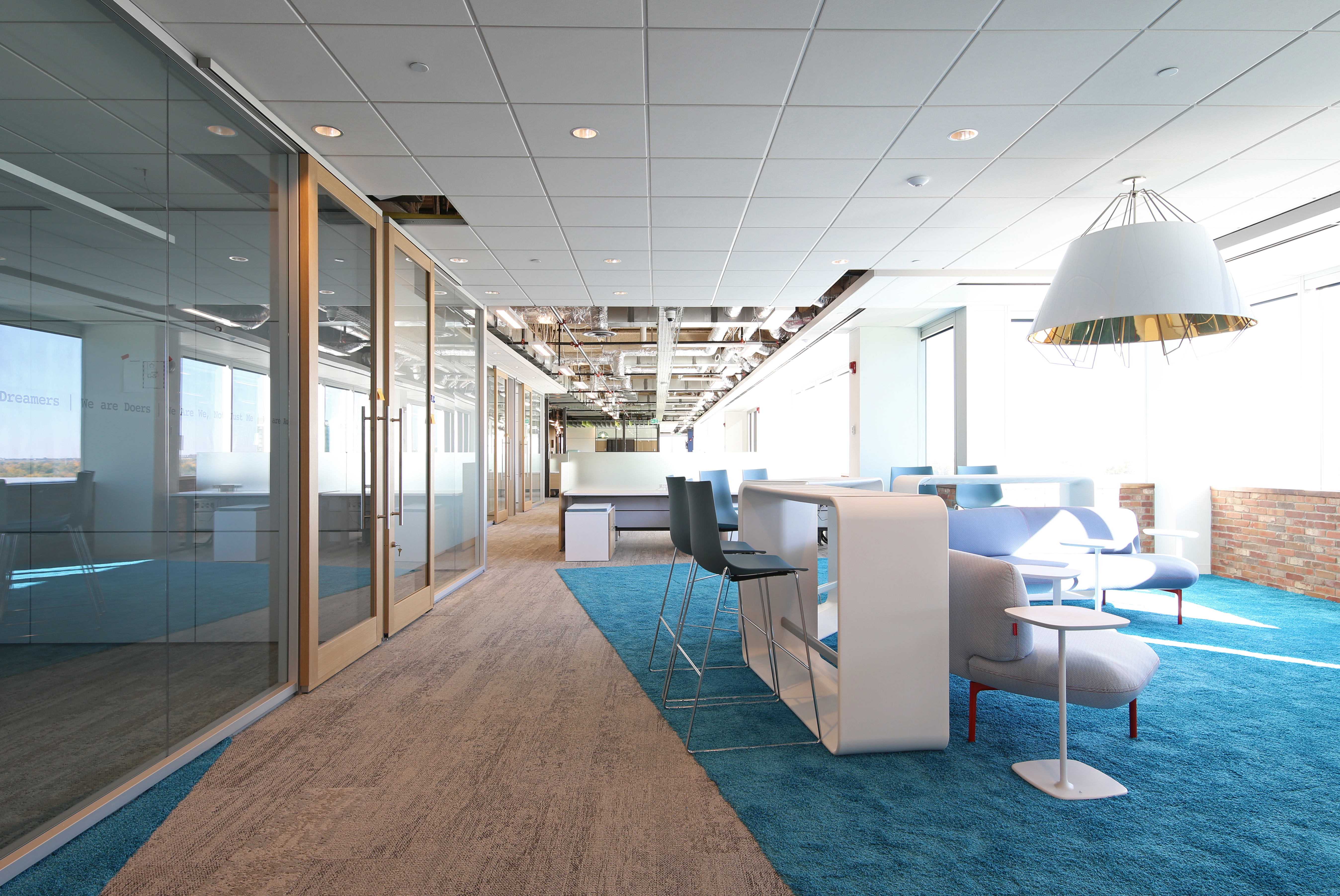 Meeting rooms on one side of an open office feature center mount glass walls and aluminum framed sliding doors.