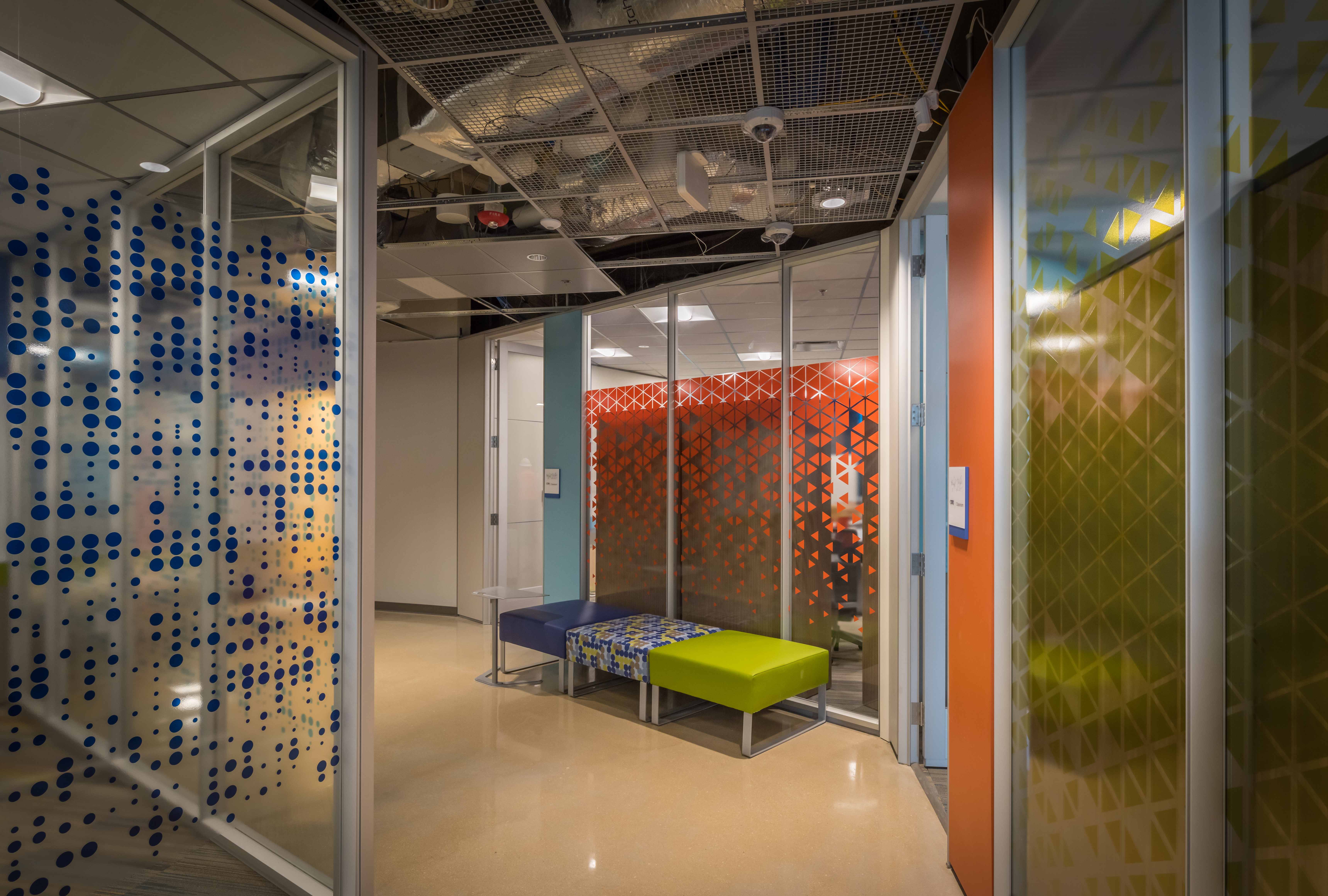 K-12 education hallway with meetings rooms behind modular glass walls, sliding doors, and custom graphics