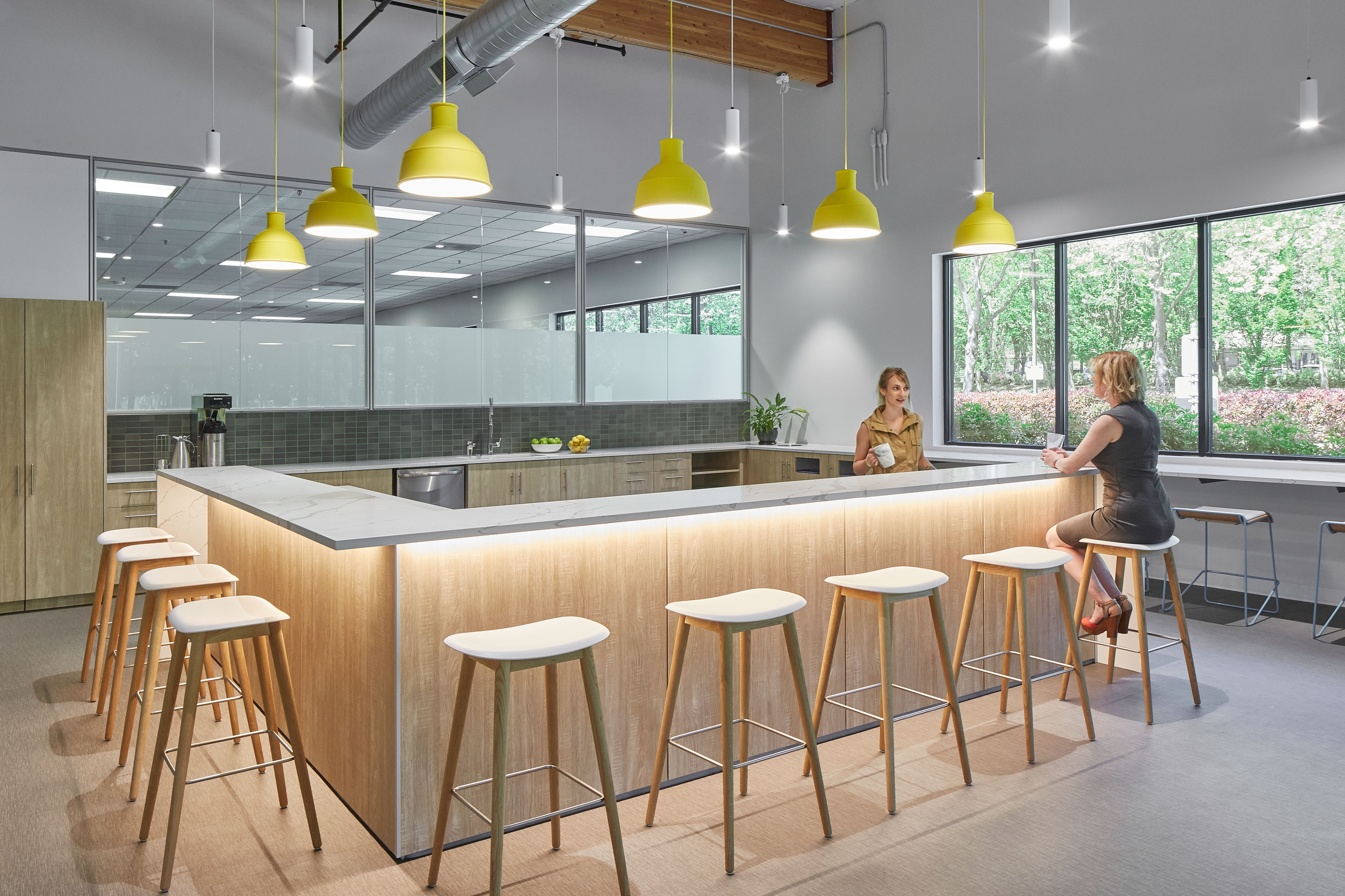 This breakroom area has DIRTT custom casework cabinetry along the back and a large eating bar that wraps around.