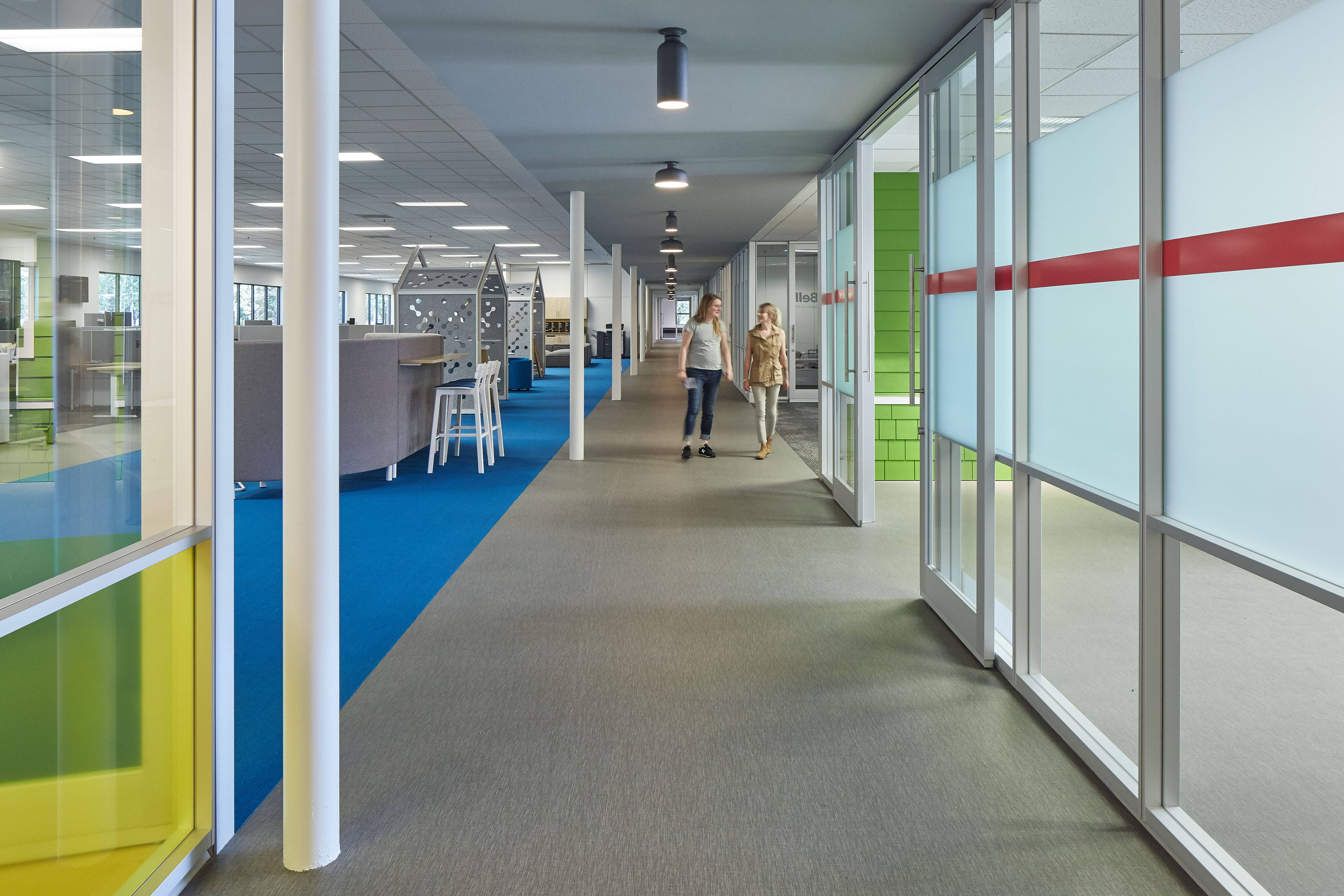 From this hallway vantage we see meeting and office areas separated by modular glass walls and sliding glass doors.