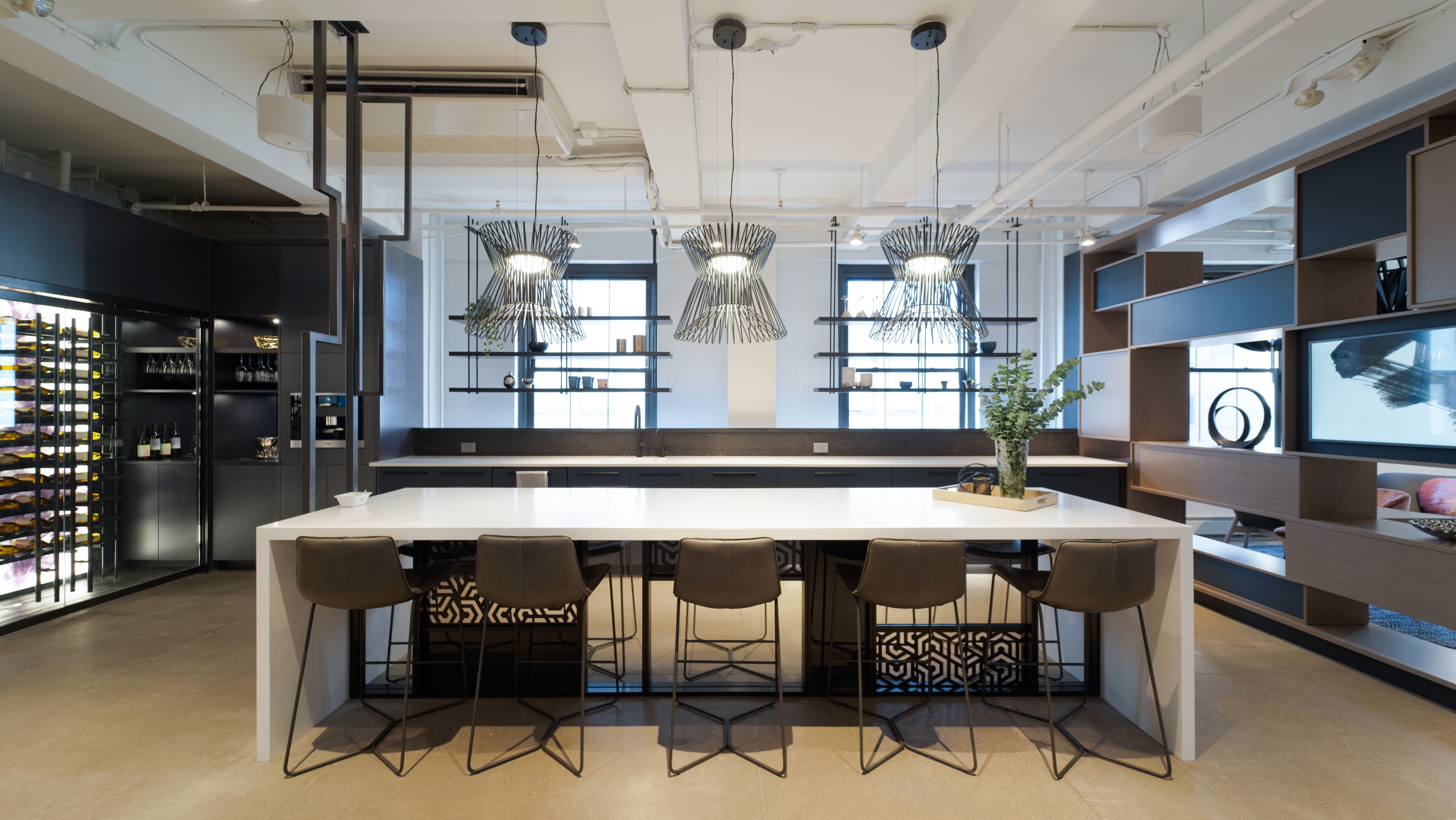 The DIRTT kitchen area has a glass walled wine room on one side and floating casework shelves on the other.