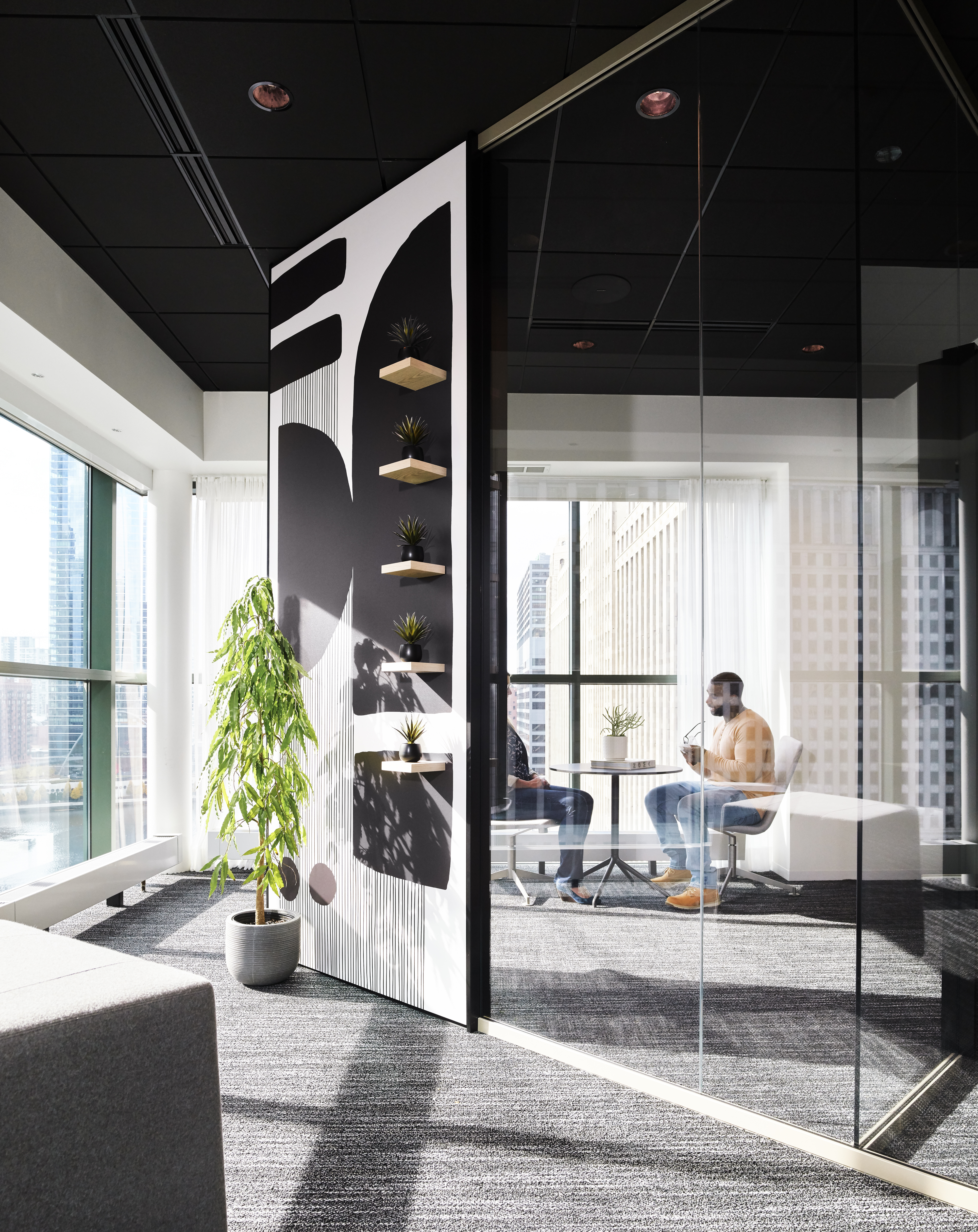 This meeting room features DIRTT's Reflect glass wall system with one solid wall that has custom graphics and shelves.