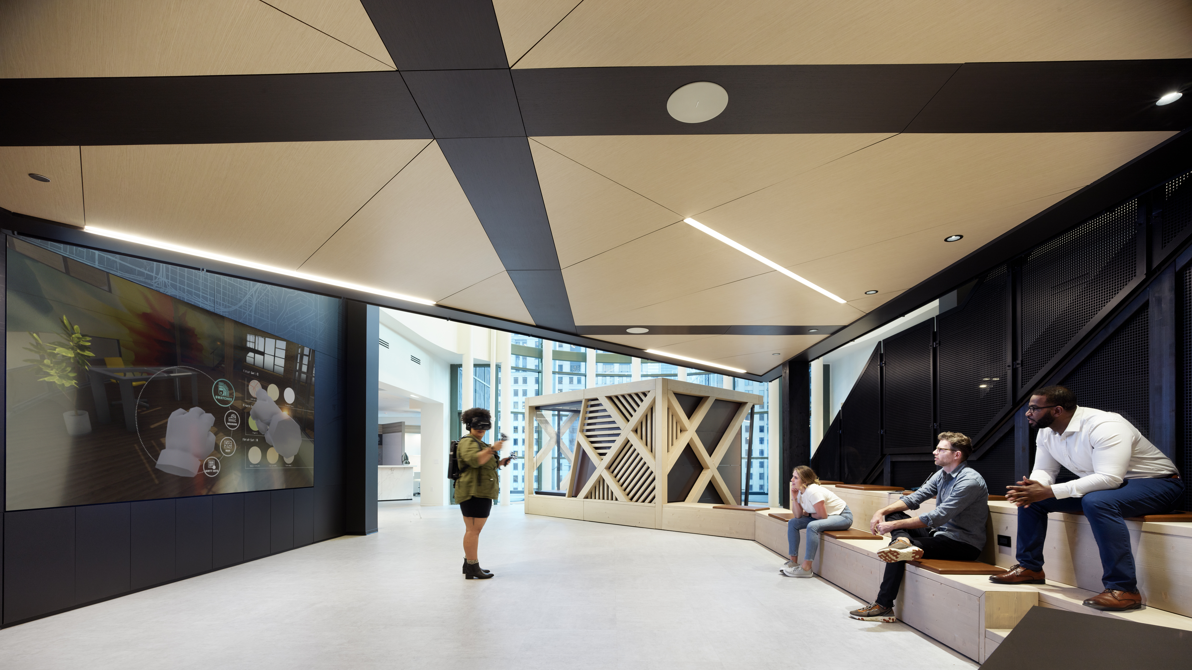 This open space VR lab in DIRTT features timber bench riser seating along the perimeter opposite a large integrated display.