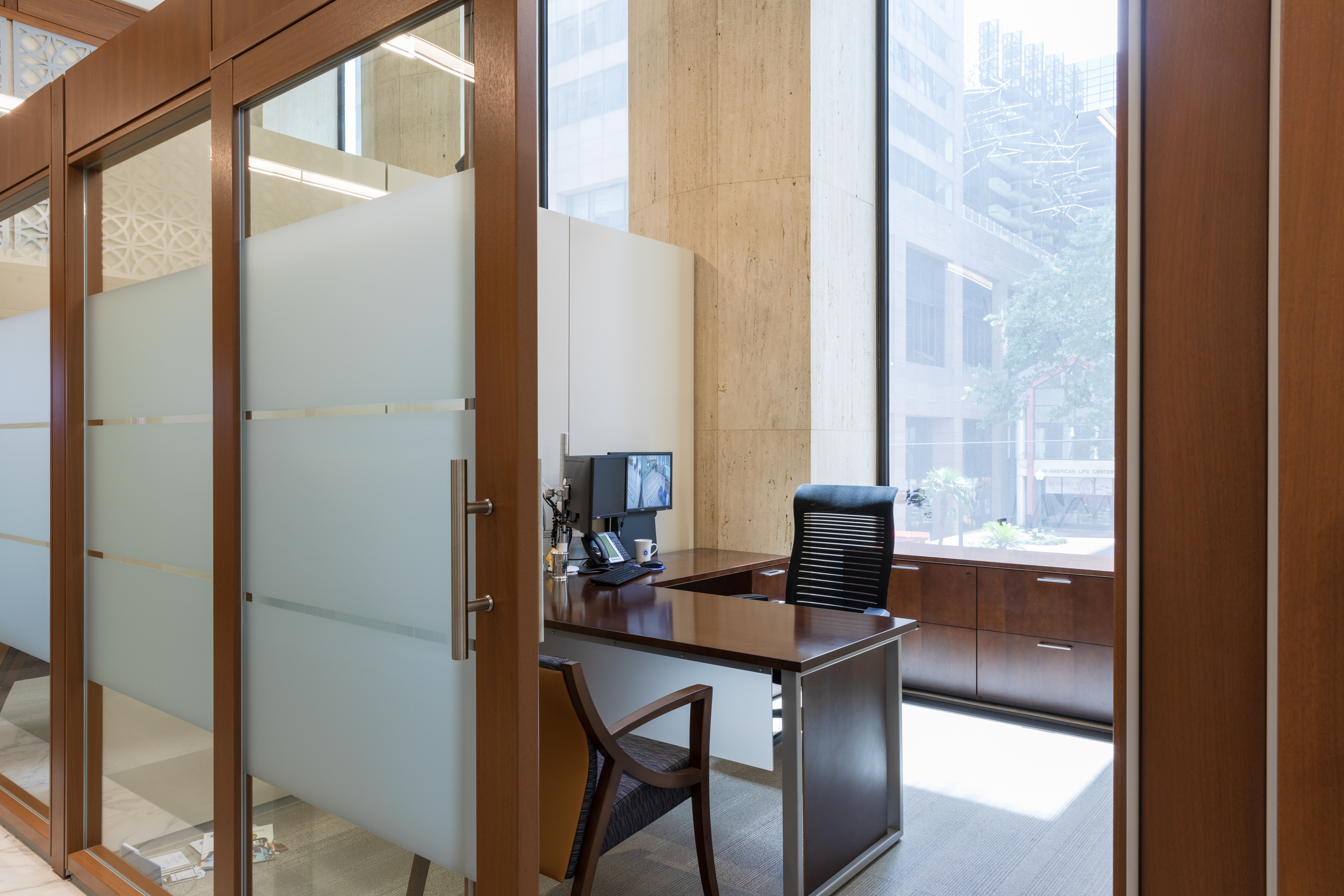 Through an open sliding glass door we see a private office with custom casework.