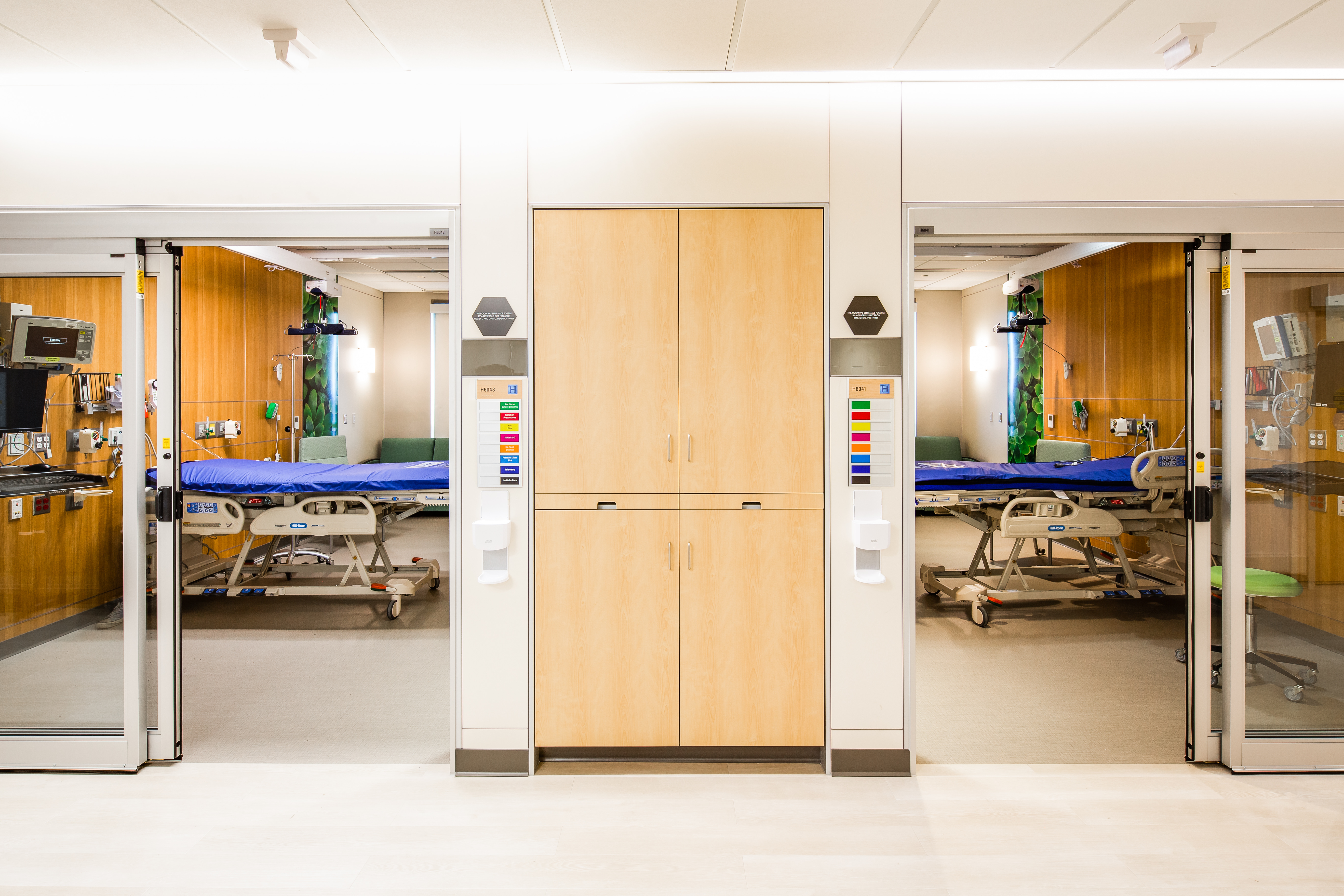 Casework cupboards with open glass sliding doors on each side to patient rooms where DIRTT's headwall solution is visible.