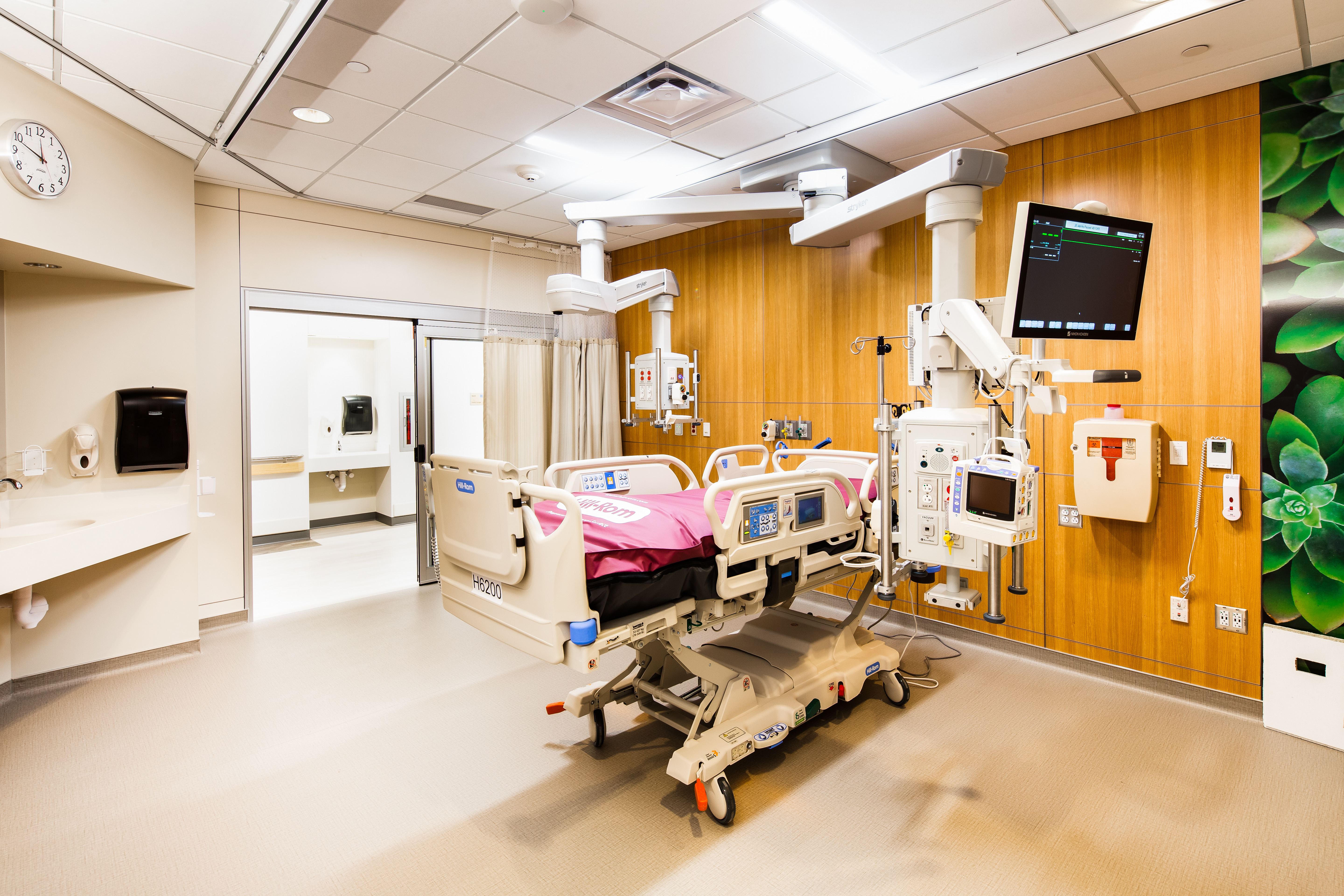 A patient room with a veneer finished DIRTT headwall that spans the length of the room.