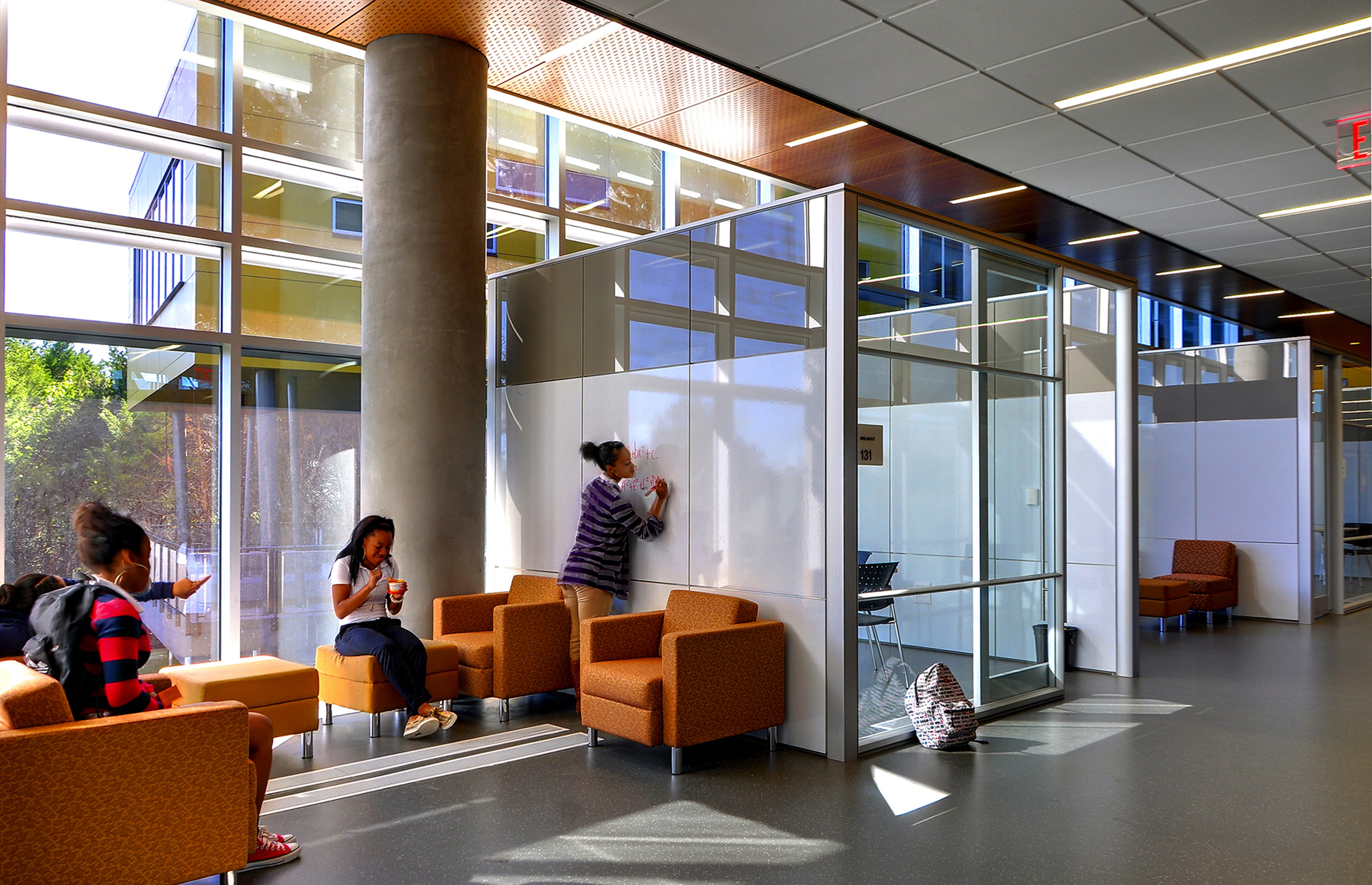 Collegiate academy open space framed with modular glass walls and writeable surfaces