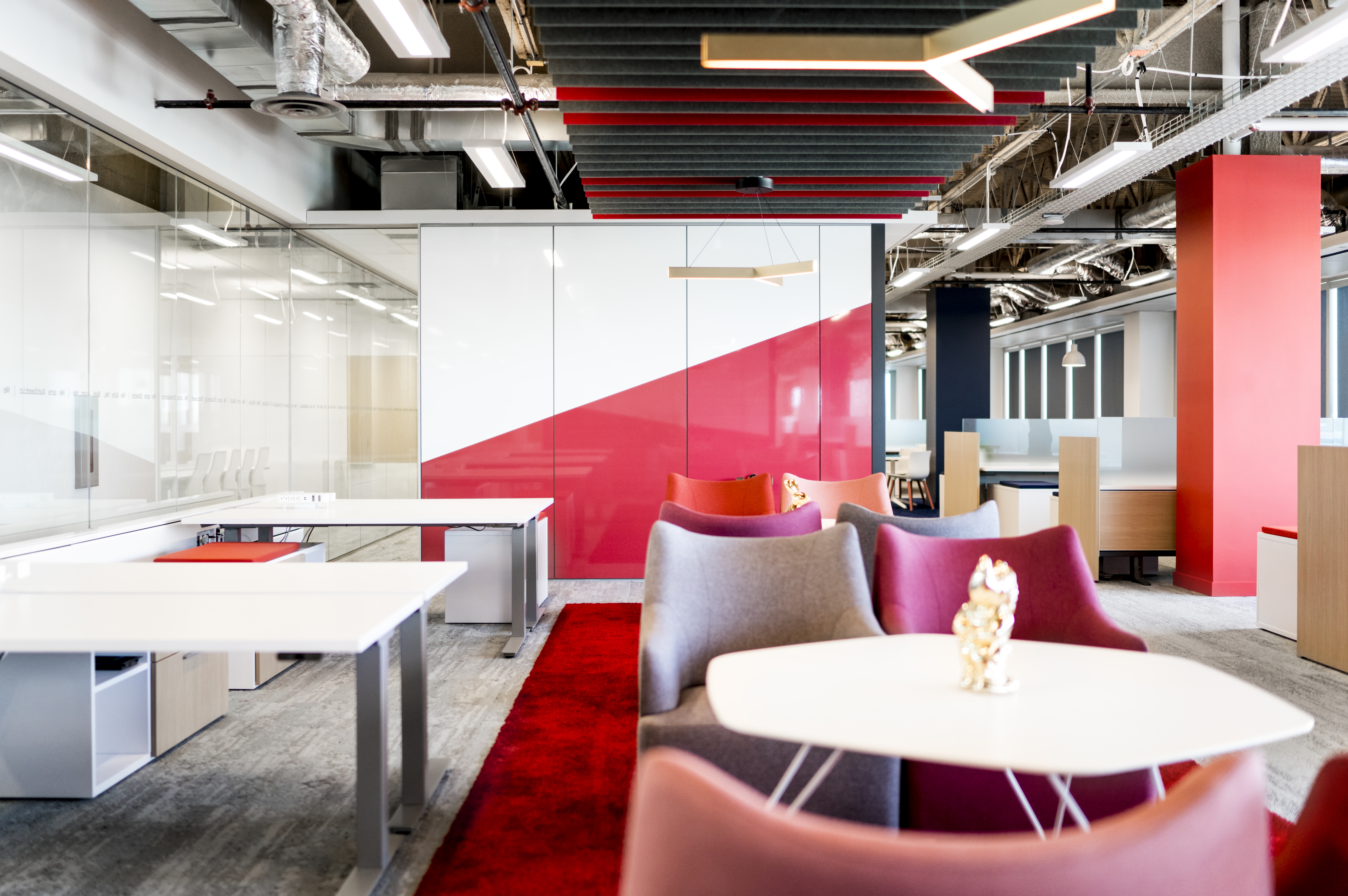 The wall separating a casual meeting space features DIRTT's center mount glass wall next to solid modular panels with a custom graphic.