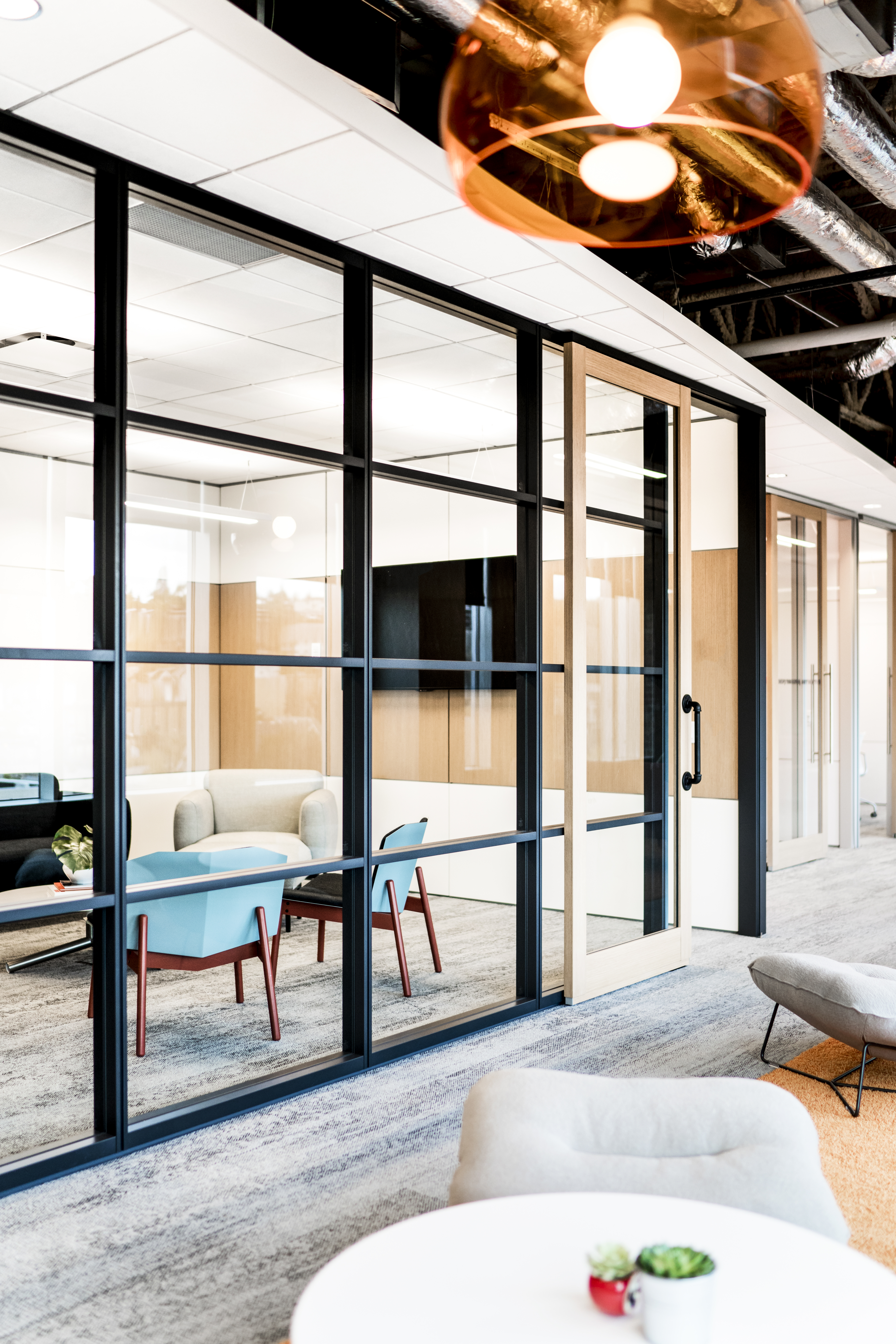 From the hallway we see a stacked modular glass wall and aluminum framed sliding glass door from DIRTT.