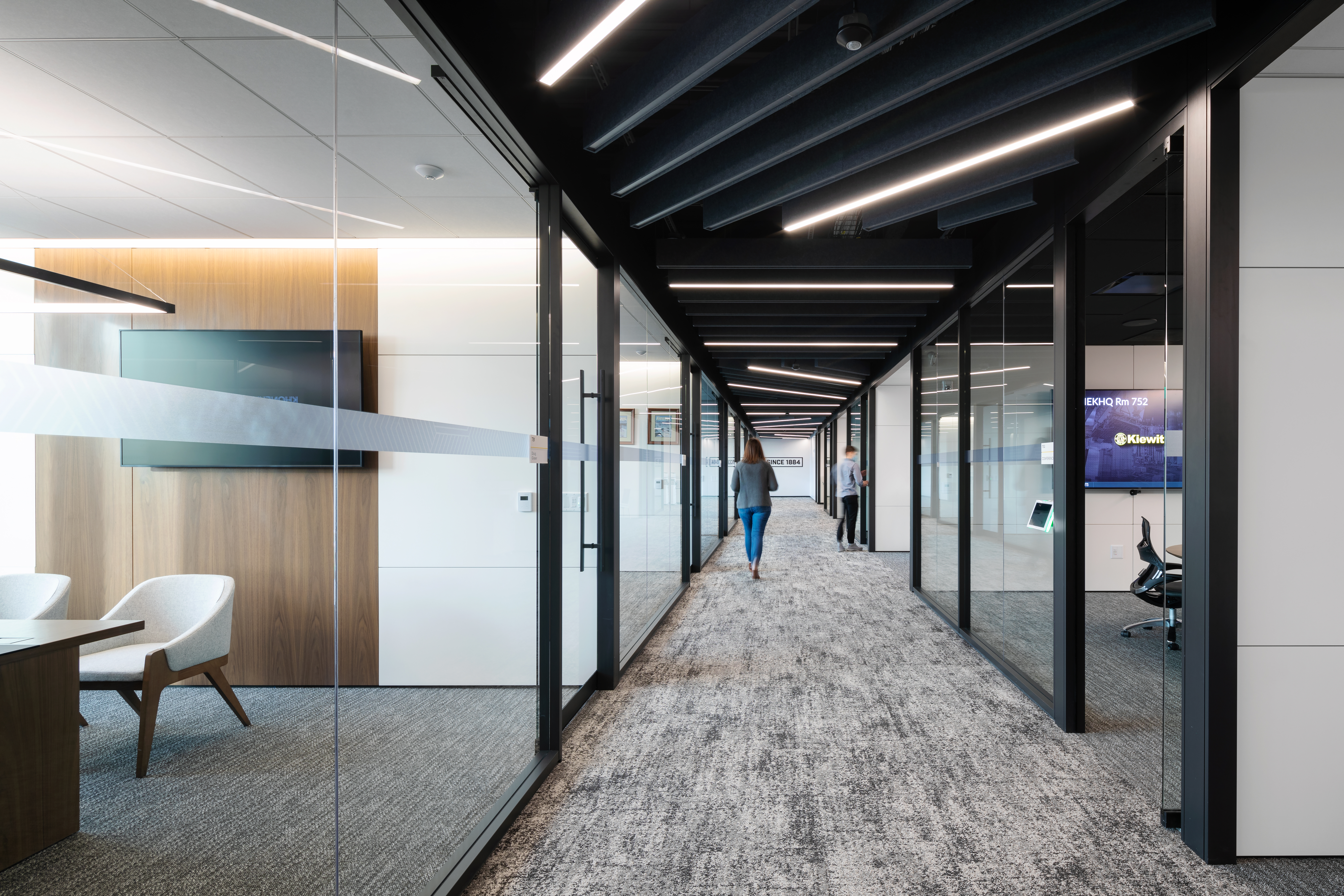 Private office spaces have been created with modular glass and solid walls, sliding glass doors, and wood veneer accents.