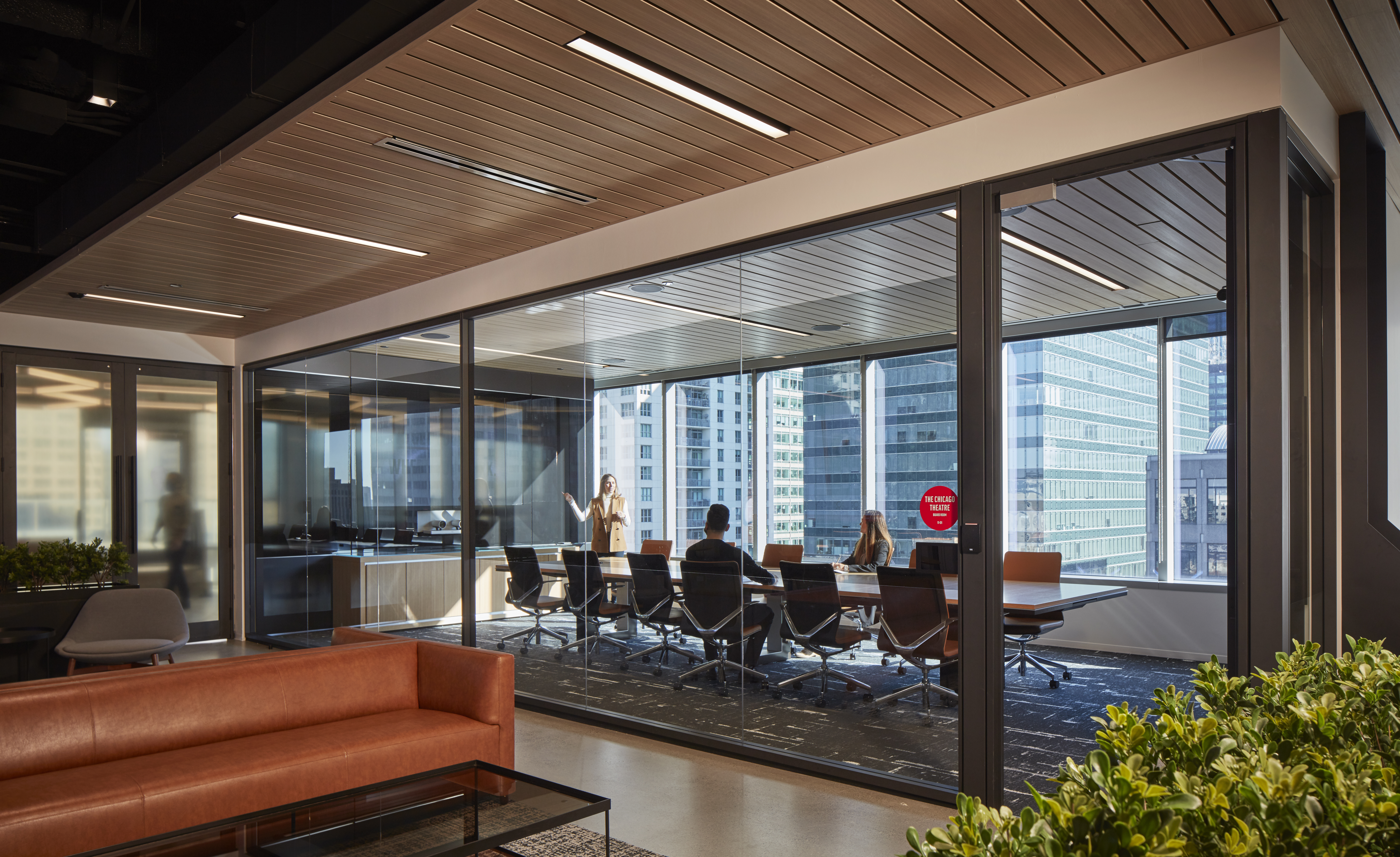 Image of a large meeting room with rich wood textures and glass wall panels forming the space to let the light in