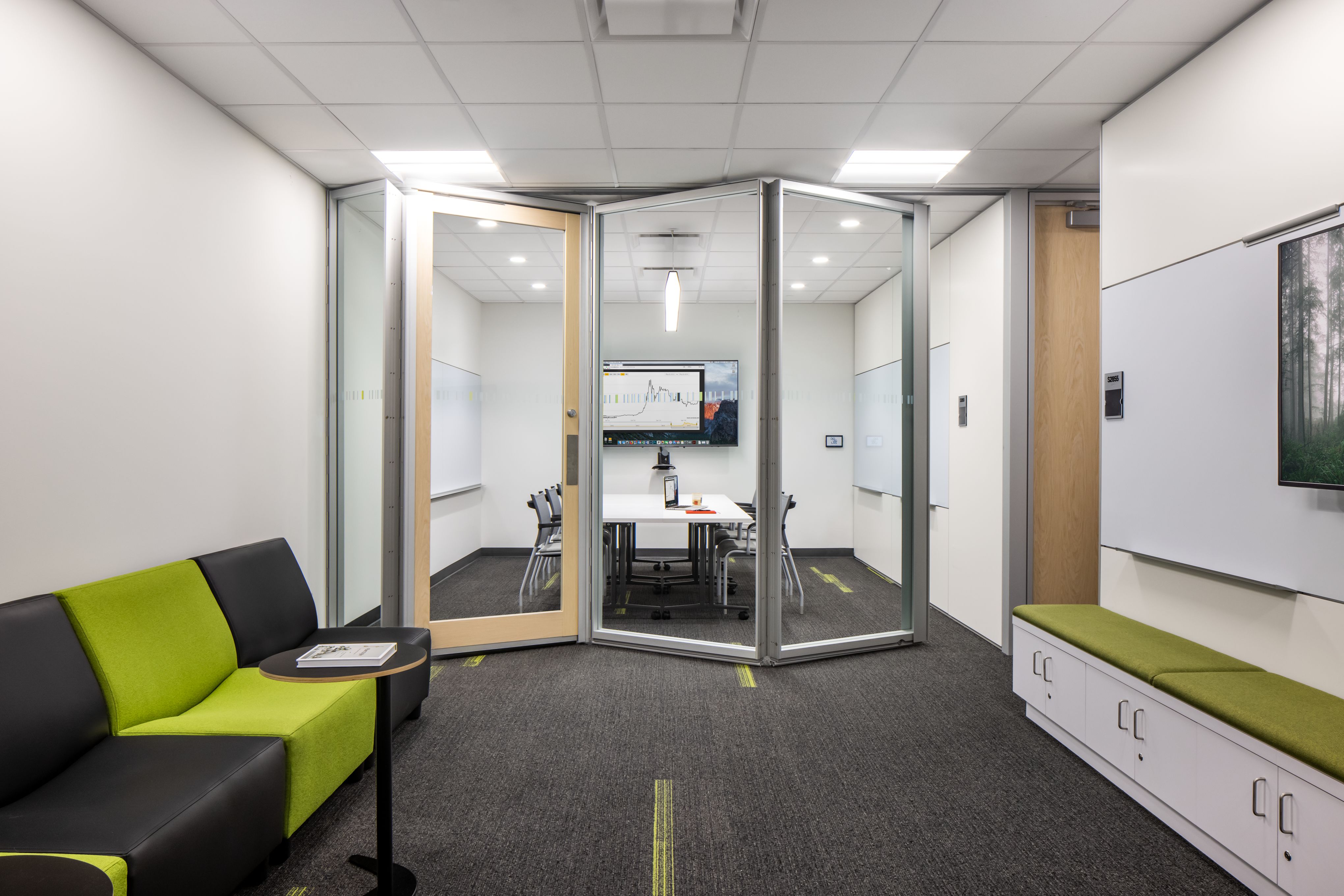 Folding glass wall system shown partially open dividing two meeting rooms