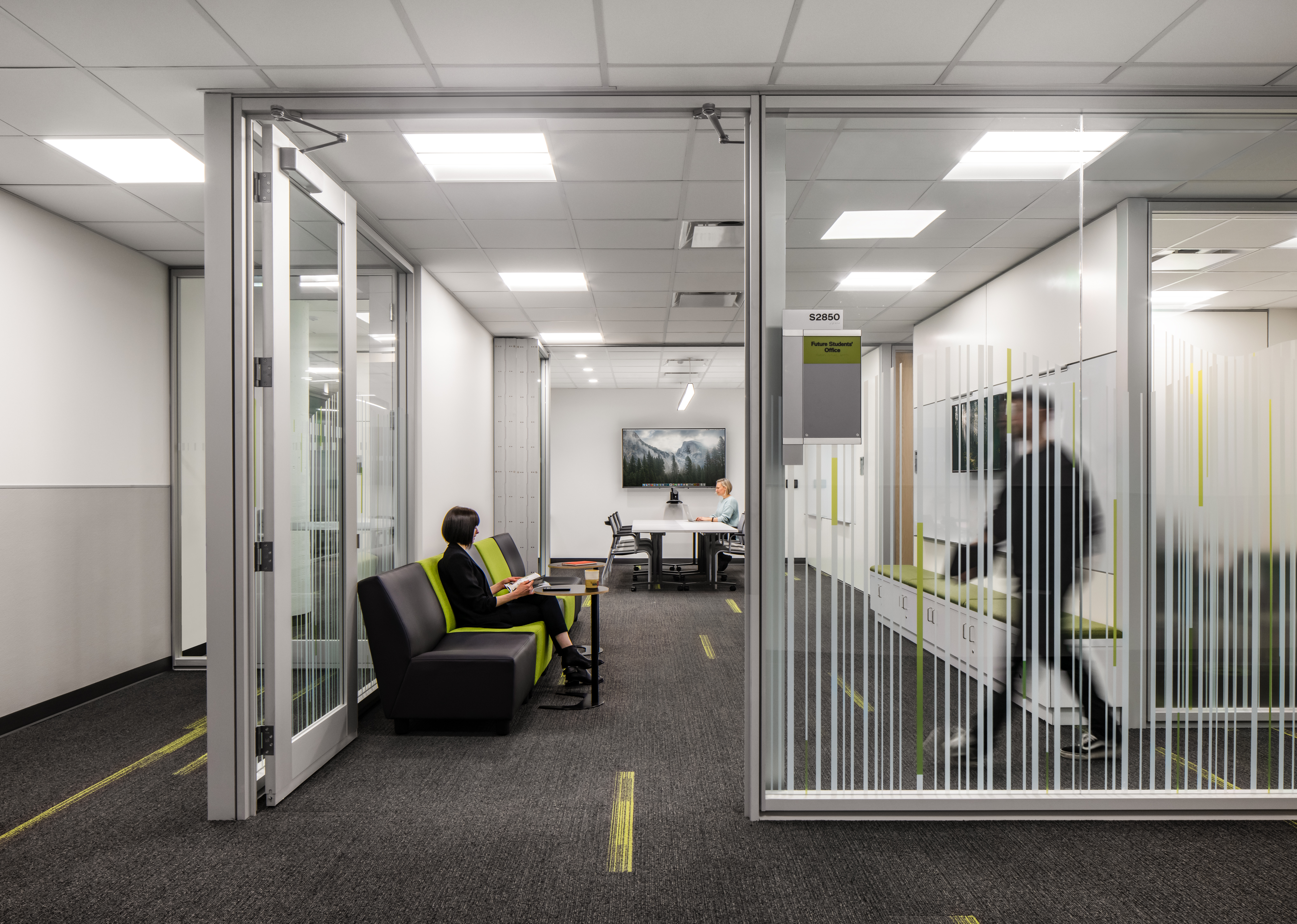 Higher ed office with mounted technology, prefab swing glass doors, and wall graphics