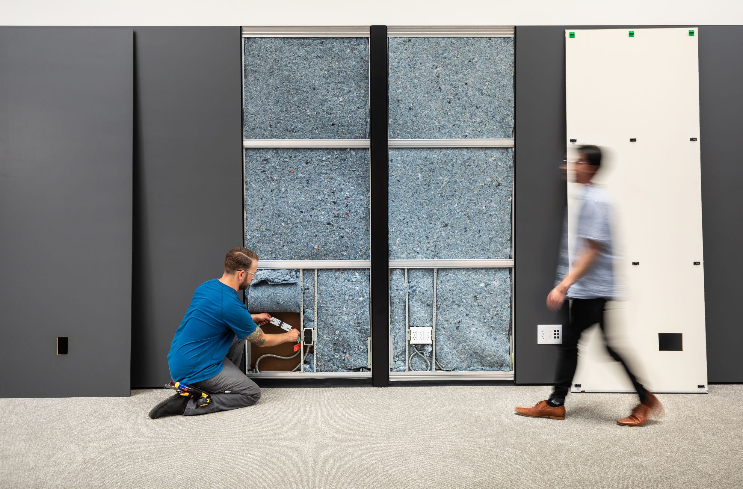 A DIRTT installer connects a modular electrical system inside a solid 2" wall.