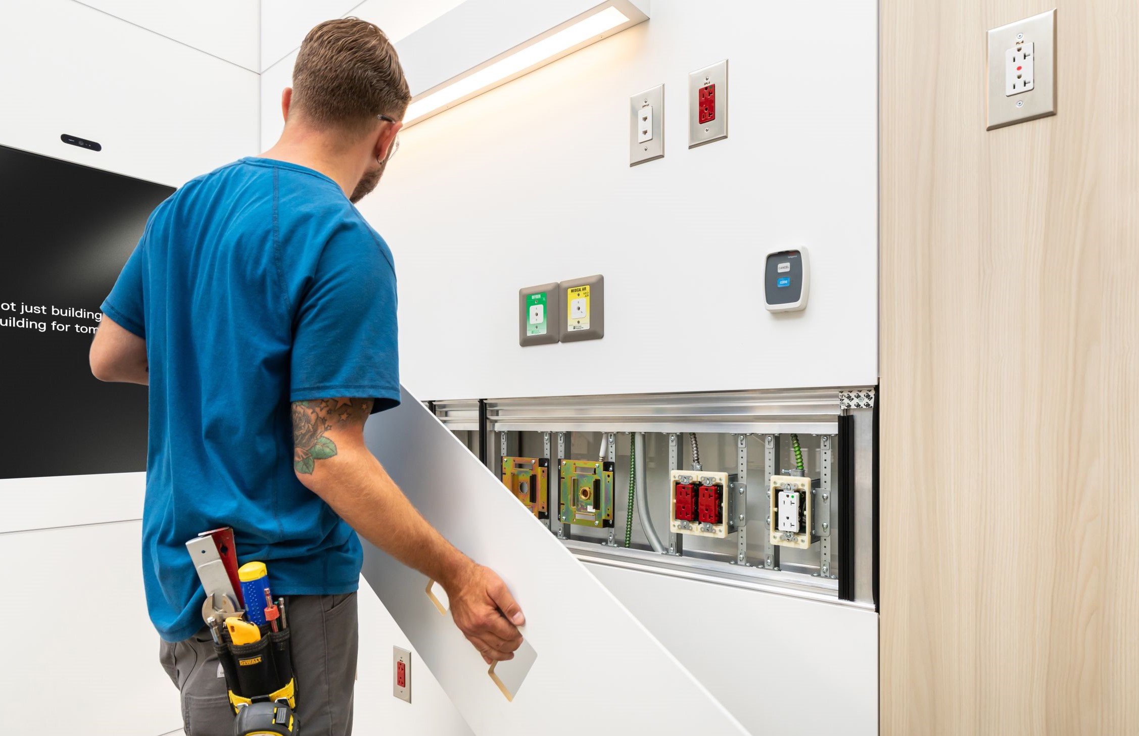 An image of a DIRTT installer taking off a solid wall panel in a healthcare headwall system with electrical and medical gaskets.