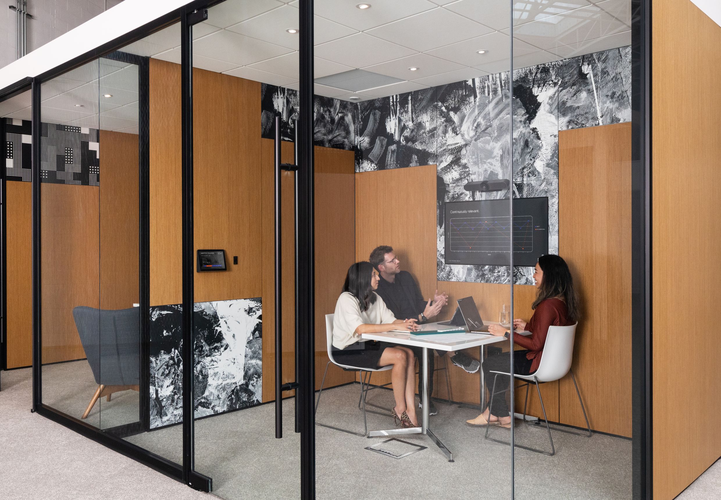 A group of employees collaborating in a meeting room built using Inspire Glass Walls and Solid 4" Walls.