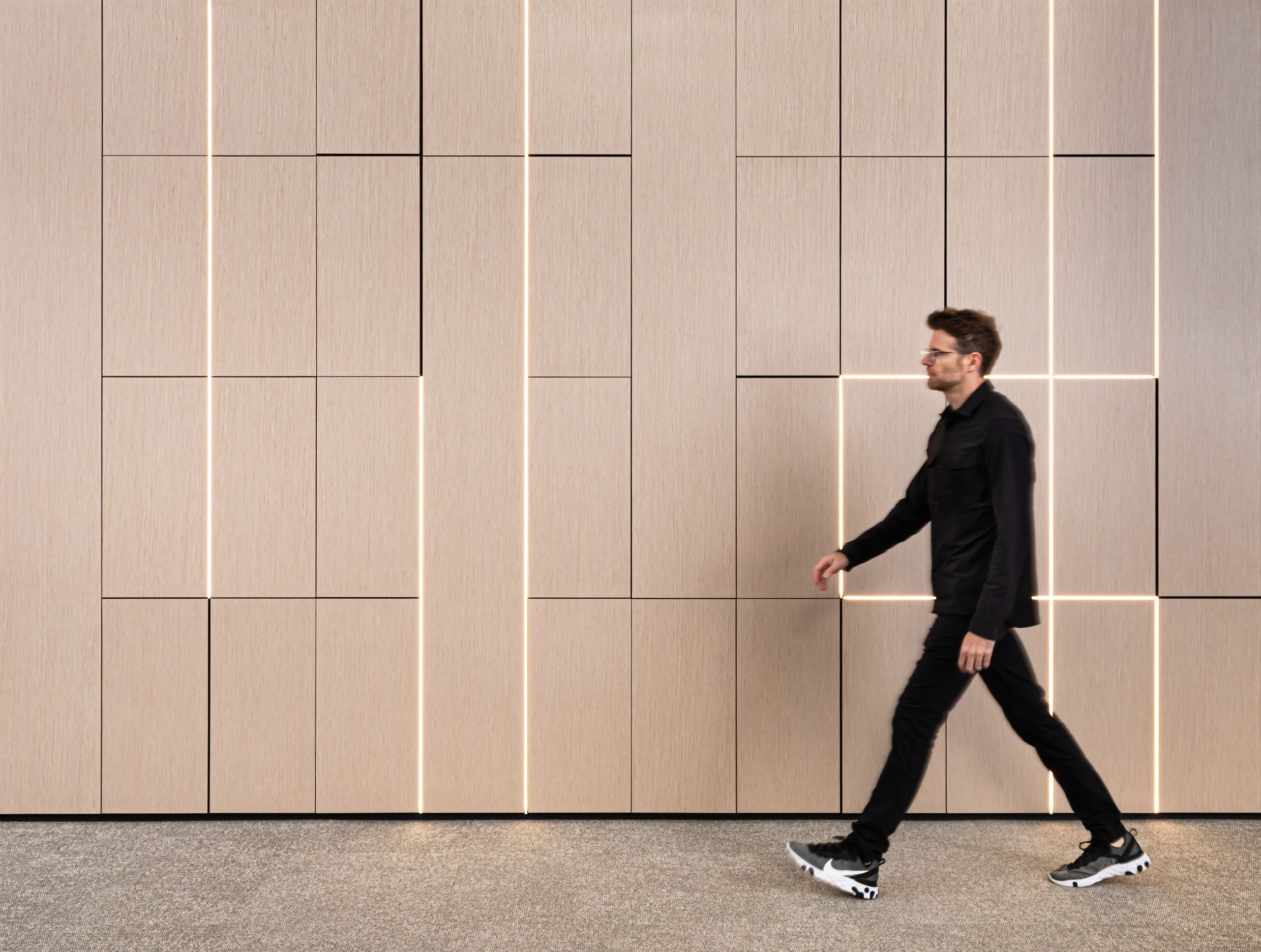A custom DIRTT wall application. This system was created using veneer wood-finished 4" solid walls with integrated LED lighting.